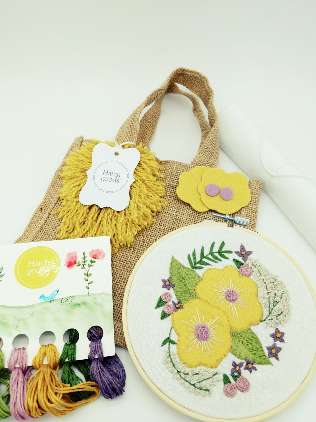 Jute bag embroidery kit includes complete project materials for felt floral pattern iron-on-ready pattern. Includes hoop, DMC thread, linen/cotton fabric, felt pieces and full stitch instructions.